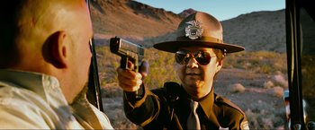 Movie still from “The Hangover Part III” (2013), directed by Todd Phillips – A man in a hat and sunglasses holding a gun in his hand; Close Up shot, Over the shoulder angle