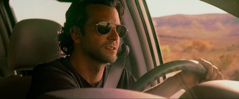 Movie still from “The Hangover Part III” (2013), directed by Todd Phillips – A man driving a car wearing sunglasses and sitting in the driver's seat; Close Up shot, Over the shoulder angle