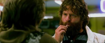 Movie still from “The Hangover Part III” (2013), directed by Todd Phillips – A man with a long beard smoking a cigarette; Close Up shot, Over the shoulder angle