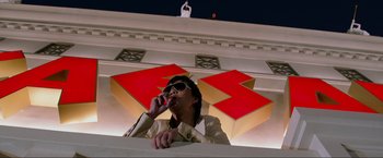 Movie still from “The Hangover Part III” (2013), directed by Todd Phillips – A man in a white jacket is drinking from a bottle; Wide shot, Low angle
