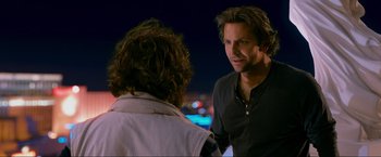 Movie still from “The Hangover Part III” (2013), directed by Todd Phillips – A man standing next to another man on a city street; Close Up shot, Over the shoulder angle