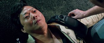 Movie still from “The Hangover Part III” (2013), directed by Todd Phillips – A man laying on the ground holding a cell phone; Close Up shot, Overhead angle