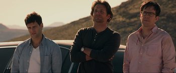 Movie still from “The Hangover Part III” (2013), directed by Todd Phillips – A man standing next to a car with his arms crossed; Medium shot, Over the shoulder angle