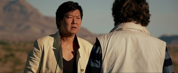 Movie still from “The Hangover Part III” (2013), directed by Todd Phillips – A man standing next to another man on a beach; Close Up shot, Over the shoulder angle