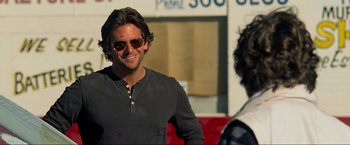 Movie still from “The Hangover Part III” (2013), directed by Todd Phillips – A person wearing sunglasses near a building; Close Up shot, Over the shoulder angle