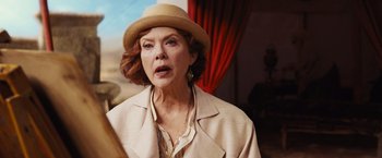 Movie still from “Death on the Nile” (2022), directed by Kenneth Branagh – An older woman wearing a hat and a beige jacket; Close Up shot, Over the shoulder angle