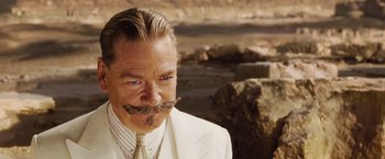 Movie still from “Death on the Nile” (2022), directed by Kenneth Branagh – A man in a white suit with a mustache; Close Up shot, Over the shoulder angle