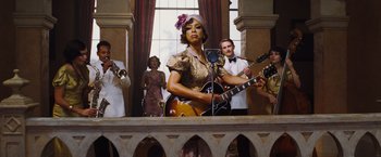 Movie still from “Death on the Nile” (2022), directed by Kenneth Branagh – A group of people that are standing around a guitar; Medium shot, Low angle