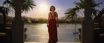 Movie still from “Death on the Nile” (2022), directed by Kenneth Branagh – A woman standing in front of a body of water; Wide shot, Low angle
