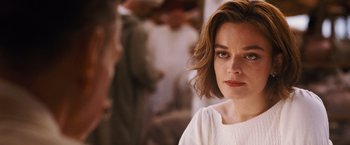 Movie still from “Death on the Nile” (2022), directed by Kenneth Branagh – A person with short brown hair; Close Up shot, Over the shoulder angle