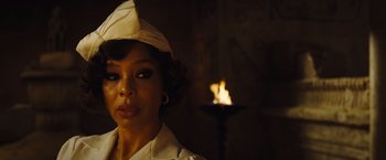 Movie still from “Death on the Nile” (2022), directed by Kenneth Branagh – A woman wearing a white hat in front of a fire; Close Up shot, Over the shoulder angle