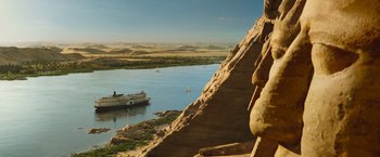 Movie still from “Death on the Nile” (2022), directed by Kenneth Branagh – A boat in the middle of a river near a cliff; Extreme Wide shot, Low angle