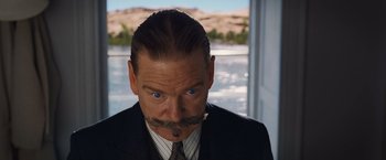 Movie still from “Death on the Nile” (2022), directed by Kenneth Branagh – A man in a suit and tie with a mustache; Close Up shot, Over the shoulder angle
