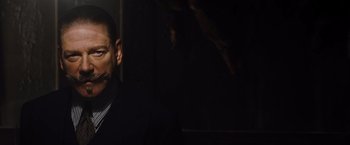 Movie still from “Death on the Nile” (2022), directed by Kenneth Branagh – A man in a suit and tie in front of a tree; Close Up shot, Low angle