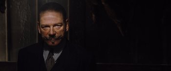 Movie still from “Death on the Nile” (2022), directed by Kenneth Branagh – A man in a suit and tie smoking a cigarette; Close Up shot, Low angle