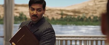 Movie still from “Death on the Nile” (2022), directed by Kenneth Branagh – A person wearing a suit and tie; Medium shot, Over the shoulder angle