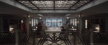 Movie still from “Death on the Nile” (2022), directed by Kenneth Branagh – A man sitting on a chair in a room; Wide shot, High angle