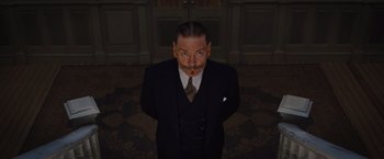 Movie still from “Death on the Nile” (2022), directed by Kenneth Branagh – A man in a suit and tie standing in front of a door; Medium shot, Low angle