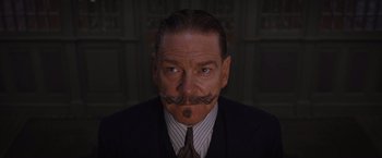 Movie still from “Death on the Nile” (2022), directed by Kenneth Branagh – A person wearing a suit and tie; Close Up shot, Low angle