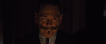 Movie still from “Death on the Nile” (2022), directed by Kenneth Branagh – A person wearing a suit and tie; Close Up shot, Low angle
