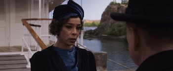 Movie still from “Death on the Nile” (2022), directed by Kenneth Branagh – A woman in a blue hat standing in front of a body of water; Close Up shot, Over the shoulder angle