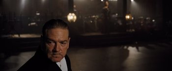 Movie still from “Death on the Nile” (2022), directed by Kenneth Branagh – A person wearing a suit and tie; Close Up shot, Over the shoulder angle