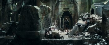 Movie still from “The Hobbit: The Battle of the Five Armies” (2014), directed by Peter Jackson – A person standing in a room with rocks and rubble; Wide shot, Low angle