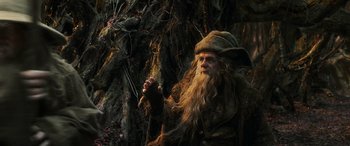 Movie still from “The Hobbit: The Battle of the Five Armies” (2014), directed by Peter Jackson – An old man with a long white beard holding a stick; Medium shot, Low angle