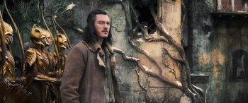 Movie still from “The Hobbit: The Battle of the Five Armies” (2014), directed by Peter Jackson – A man with long black hair standing in front of a wall; Medium shot, Low angle