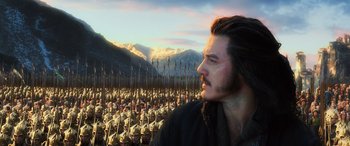 Movie still from “The Hobbit: The Battle of the Five Armies” (2014), directed by Peter Jackson – A man with long hair and a beard standing in front of a group of soldiers; Close Up shot, Low angle