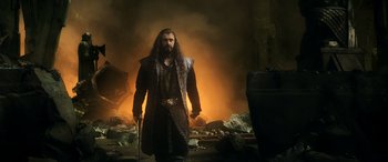 Movie still from “The Hobbit: The Battle of the Five Armies” (2014), directed by Peter Jackson – A man with long hair holding a sword in front of a fire; Medium shot, Low angle