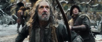 Movie still from “The Hobbit: The Battle of the Five Armies” (2014), directed by Peter Jackson – An old man with a long beard holding a bow and arrow; Close Up shot, Low angle
