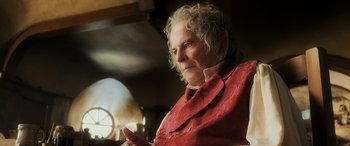 Movie still from “The Hobbit: The Battle of the Five Armies” (2014), directed by Peter Jackson – An older woman wearing a red jacket looking at the camera; Close Up shot, Low angle