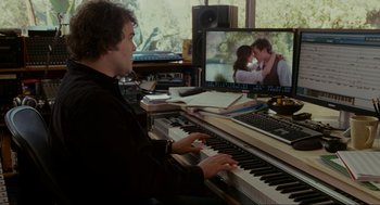 Movie still from “The Holiday” (2006), directed by Nancy Meyers – A man playing the piano in front of a computer screen; Medium shot, Over the shoulder angle
