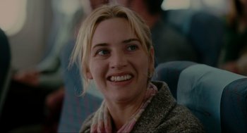 Movie still from “The Holiday” (2006), directed by Nancy Meyers – A person sitting in a chair smiling; Close Up shot, Over the shoulder angle