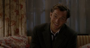 Movie still from “The Holiday” (2006), directed by Nancy Meyers – A man wearing a suit and smiling for the camera; Close Up shot, Over the shoulder angle