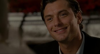Movie still from “The Holiday” (2006), directed by Nancy Meyers – A person wearing a suit and smiling; Close Up shot, Over the shoulder angle