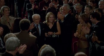 Movie still from “The Holiday” (2006), directed by Nancy Meyers – A group of people standing in front of a group of people clapping; Medium shot, Over the shoulder angle