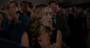 Movie still from “The Holiday” (2006), directed by Nancy Meyers – A person sitting in a crowd of people; Close Up shot, Over the shoulder angle