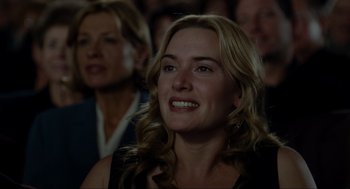 Movie still from “The Holiday” (2006), directed by Nancy Meyers – A person sitting in front of an audience; Close Up shot, Over the shoulder angle