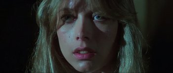 Movie still from “The House by the Cemetery” (1981), directed by Lucio Fulci – A woman's face in a dimly - lit room; Close Up shot, Low angle