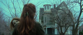 Movie still from “The House by the Cemetery” (1981), directed by Lucio Fulci – A woman standing in front of an old house; Wide shot, Low angle