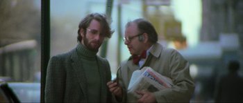 Movie still from “The House by the Cemetery” (1981), directed by Lucio Fulci – Two men are talking to each other while holding newspapers; Medium shot, Low angle