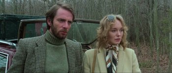Movie still from “The House by the Cemetery” (1981), directed by Lucio Fulci – A man and a woman standing next to each other in front of a car; Close Up shot, Low angle