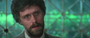 Movie still from “The House by the Cemetery” (1981), directed by Lucio Fulci – A person wearing glasses and a suit; Close Up shot, Over the shoulder angle