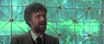 Movie still from “The House by the Cemetery” (1981), directed by Lucio Fulci – A man in a suit and glasses is smiling for the camera; Close Up shot, Low angle