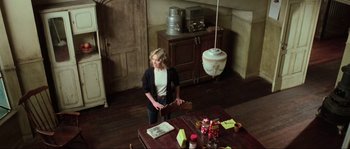 Movie still from “The House by the Cemetery” (1981), directed by Lucio Fulci – A woman standing at a table in a room; Wide shot, High angle