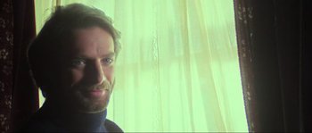 Movie still from “The House by the Cemetery” (1981), directed by Lucio Fulci – A man standing in front of a window with green curtains; Close Up shot, Low angle