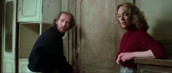 Movie still from “The House by the Cemetery” (1981), directed by Lucio Fulci – A man and a woman standing next to each other in front of a door; Medium shot, Over the shoulder angle