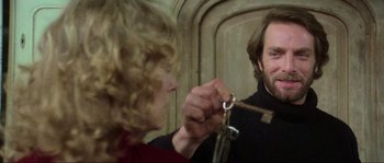 Movie still from “The House by the Cemetery” (1981), directed by Lucio Fulci – A man is holding a key to a woman's hand; Close Up shot, Over the shoulder angle